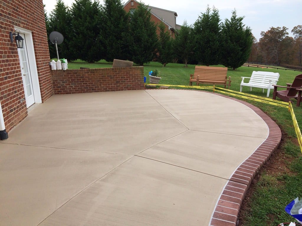 Newly finished concrete patio with decorative brick border at a Rochester, NH home
