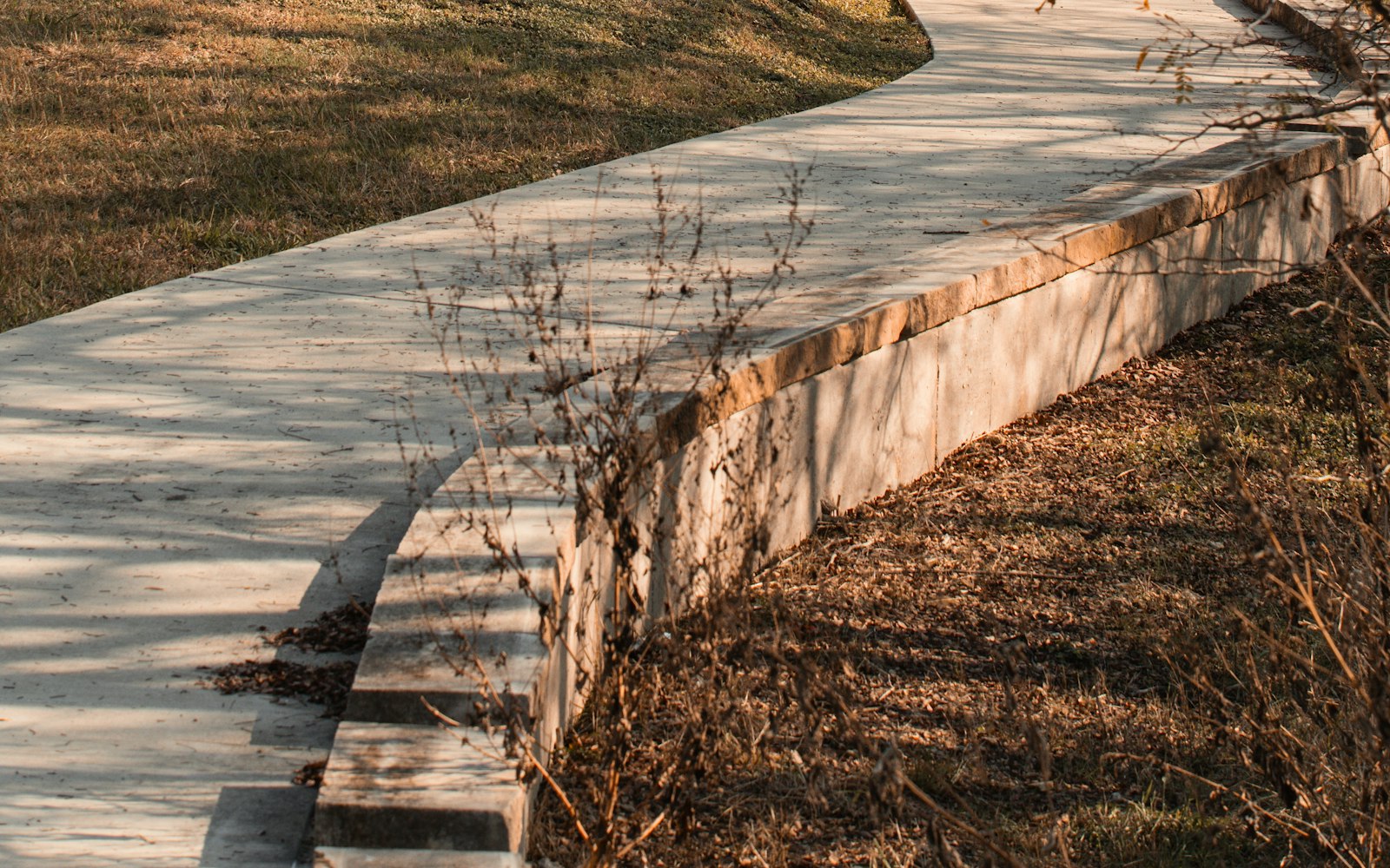 A curving poured concrete walkway with a clean finished edge running alongside a New Hampshire home