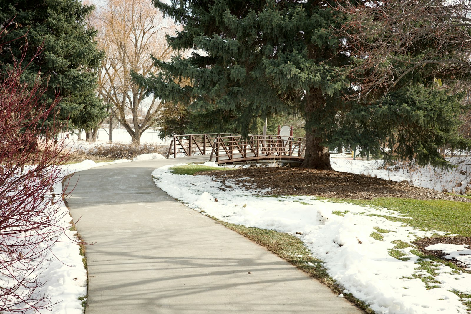 Concrete walkway holding firm next to melting snow after a New Hampshire winter