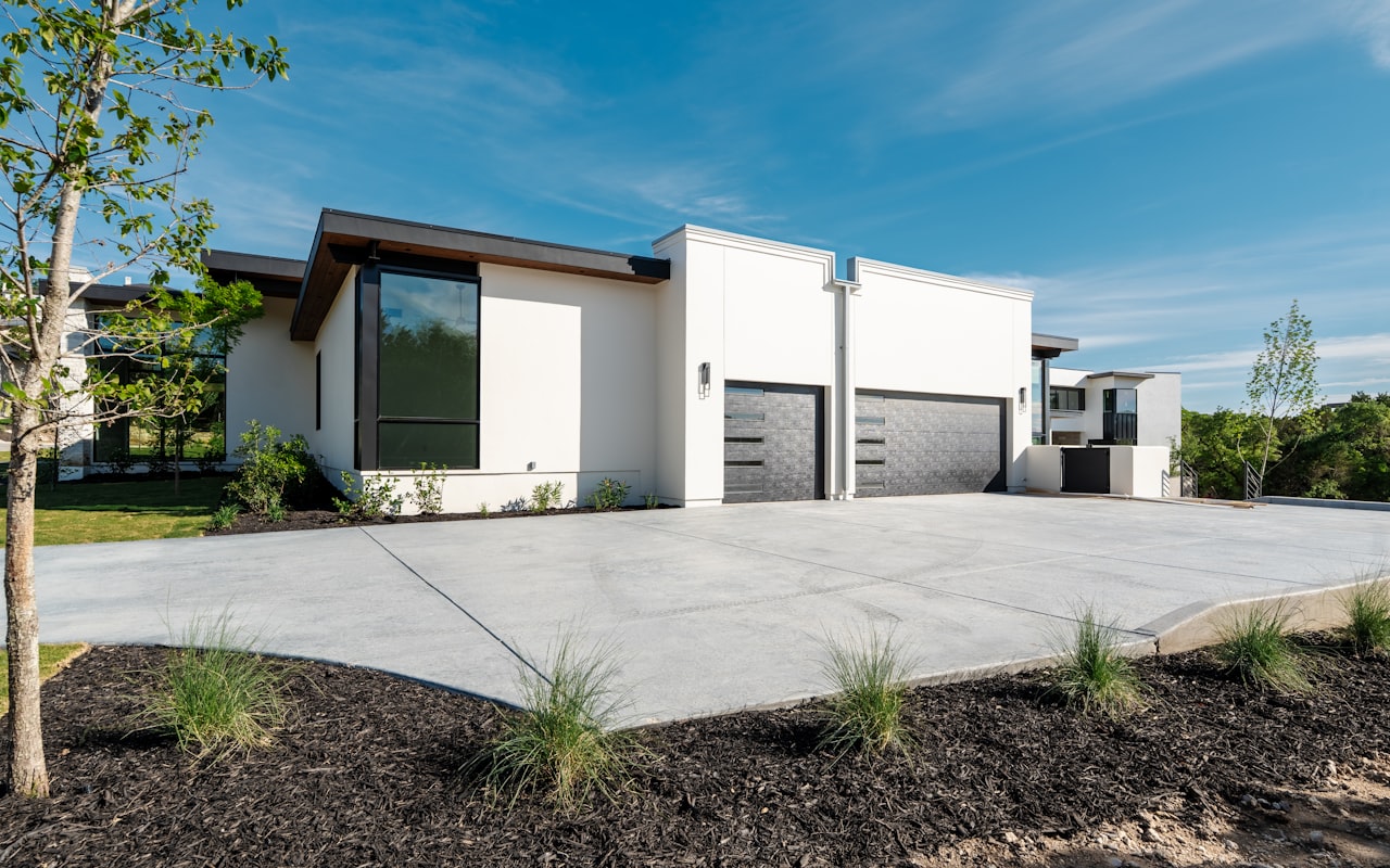 Finished light-gray residential concrete driveway apron in front of a modern home — example of a completed concrete driveway near Rochester, NH