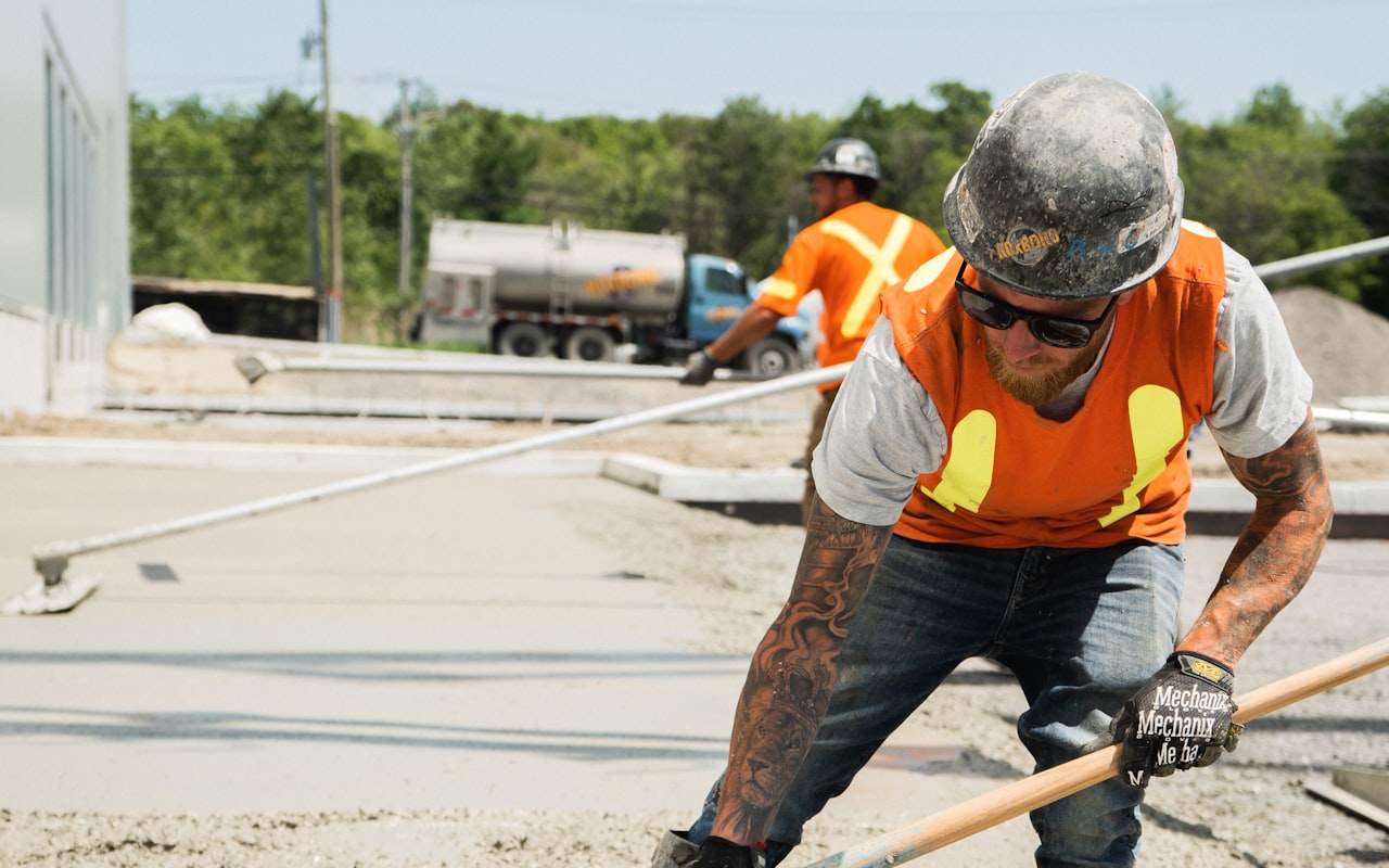 Concrete contractor screeding and finishing a freshly poured concrete driveway slab on a New England job site near Rochester, NH