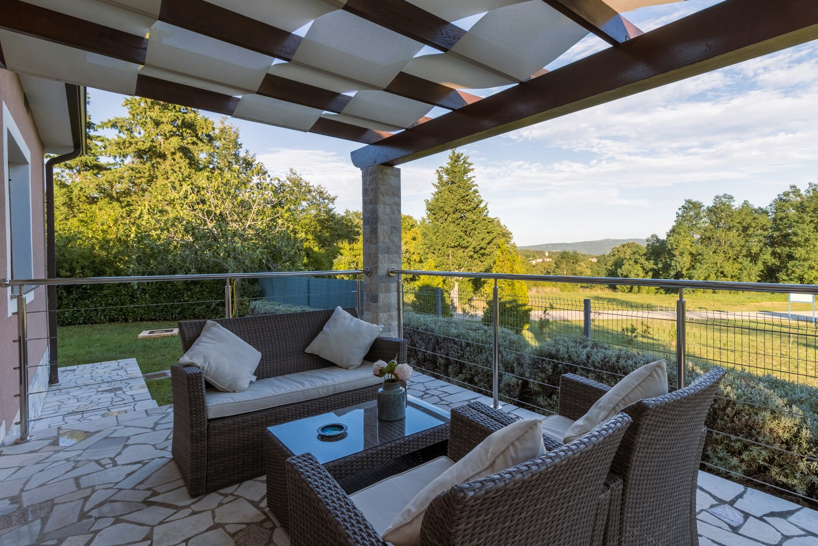 Outdoor living space with a decorative paved patio, lounge seating, and a covered area overlooking a green New England yard
