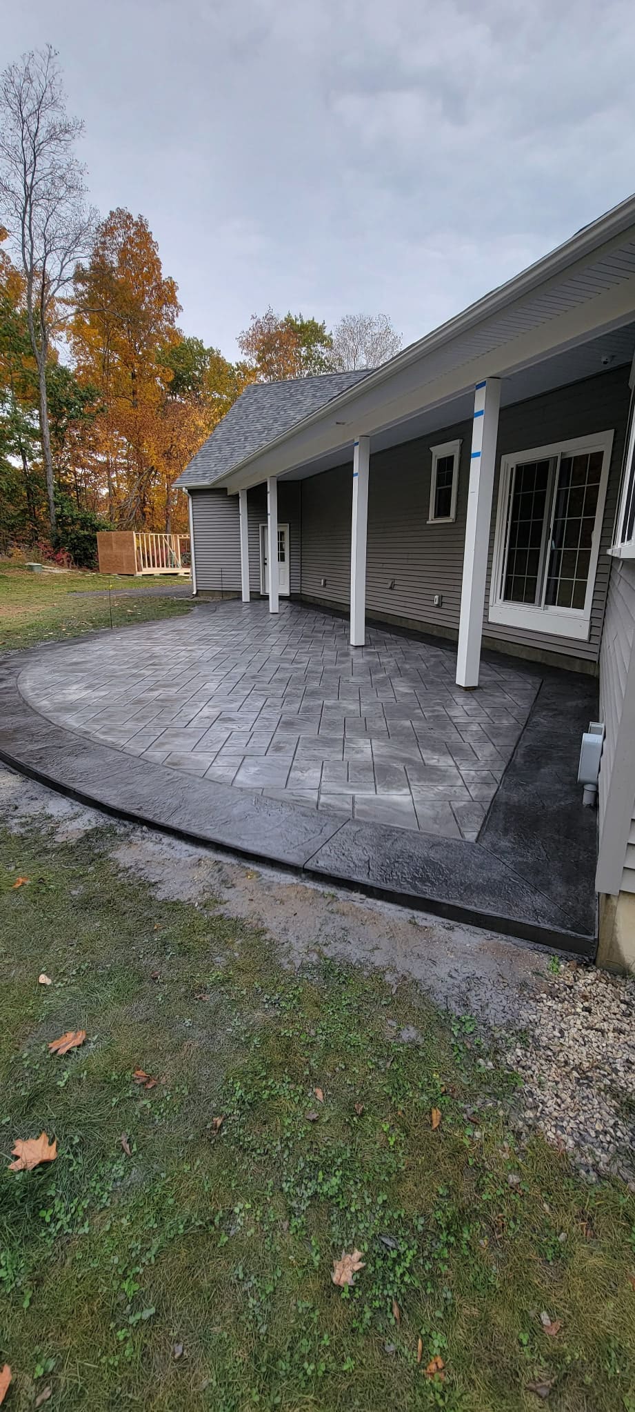 Finished stamped concrete patio with an ashlar slate pattern wrapping the back of a Rochester, NH home
