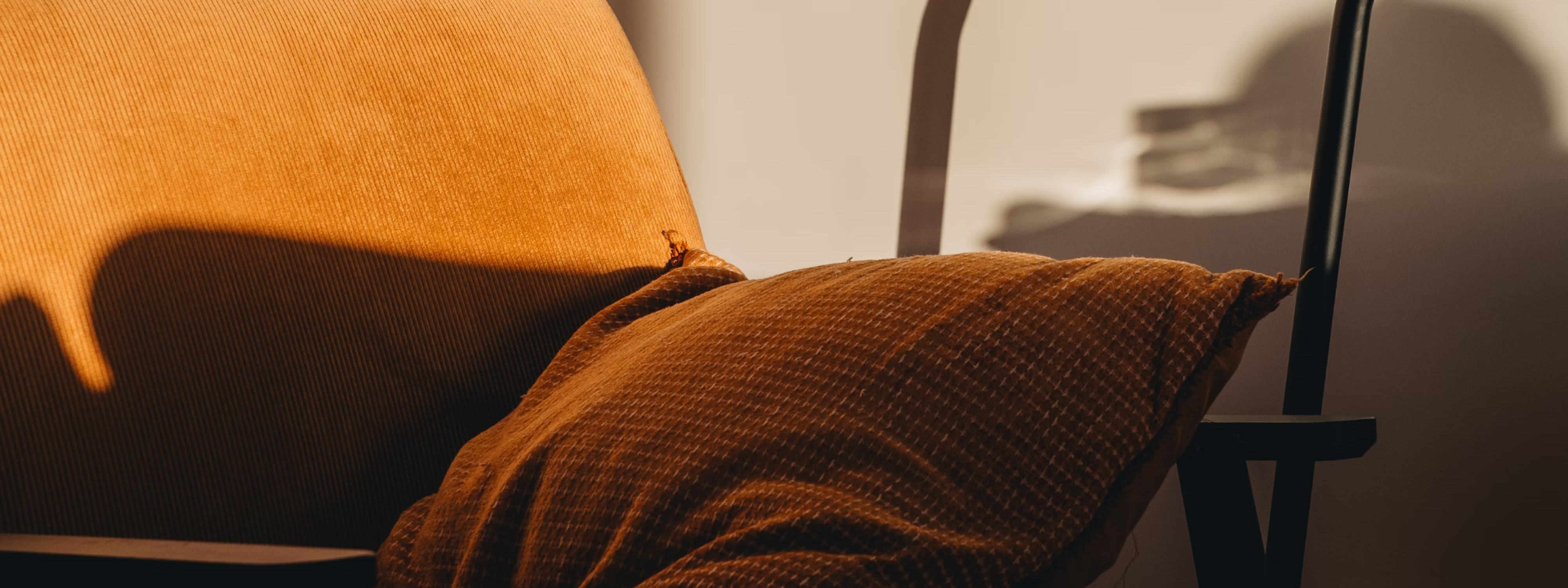 Warm orange fabric cushion draped on a chair with soft shadows