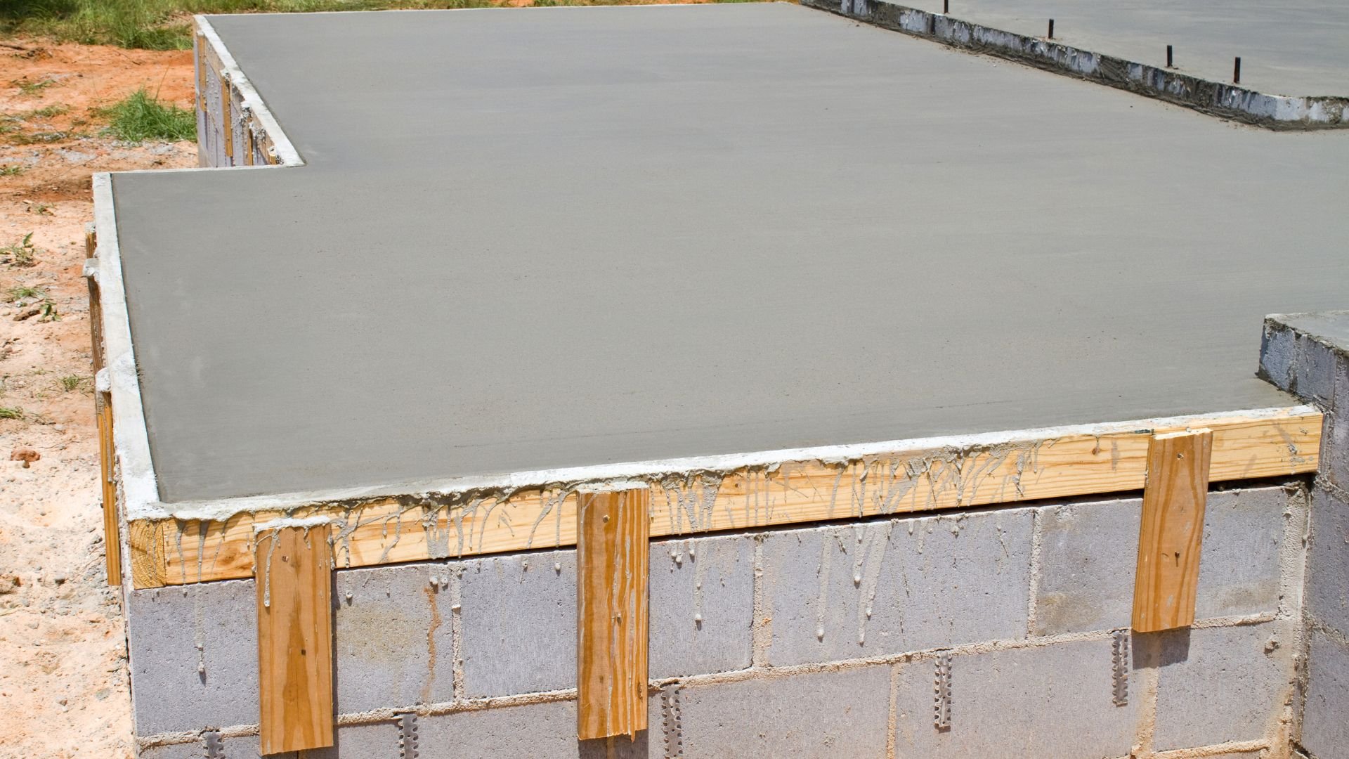 Freshly poured concrete slab with wooden formwork and concrete block foundation