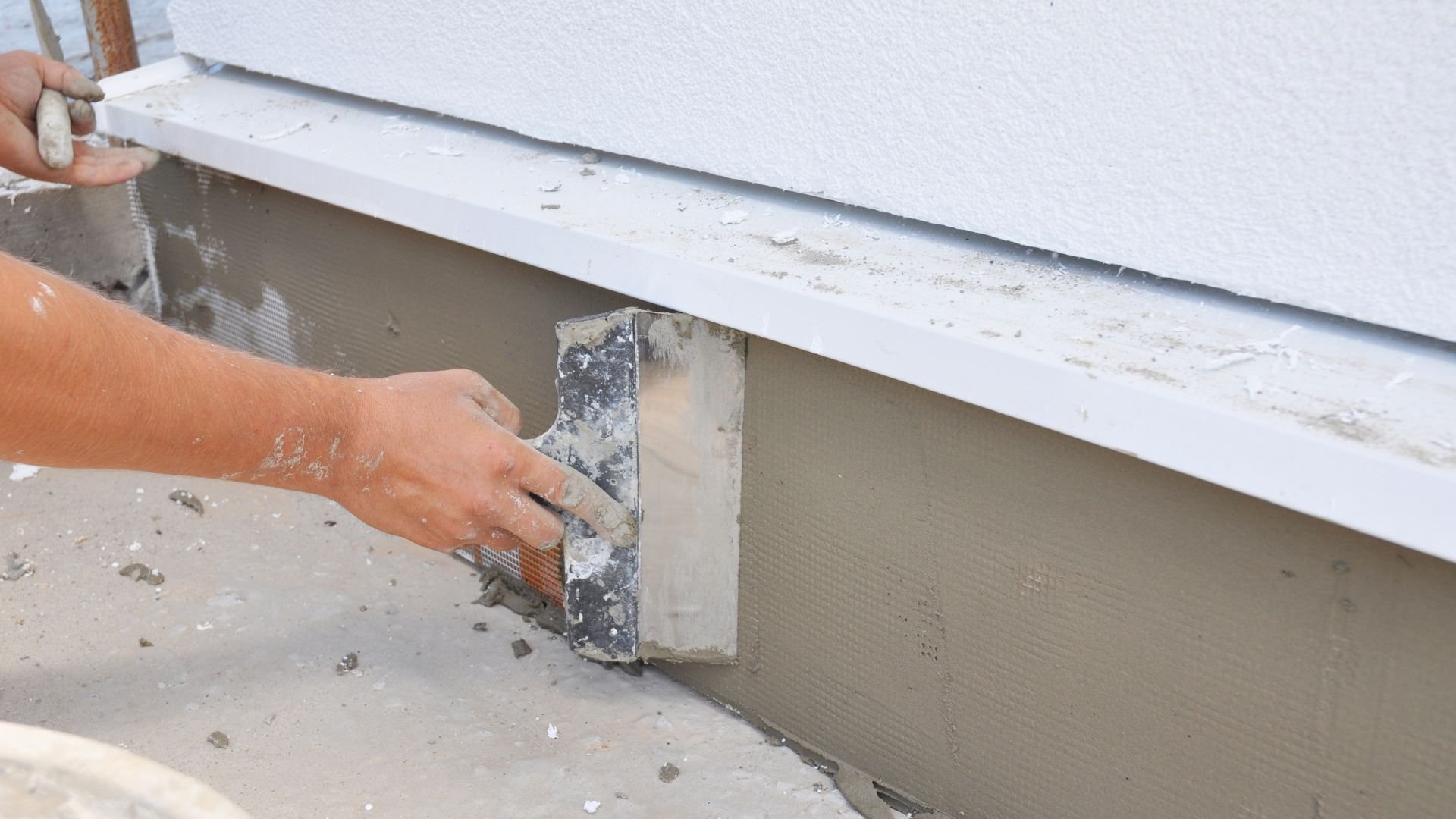 Construction worker applying cement plaster to wall with trowel