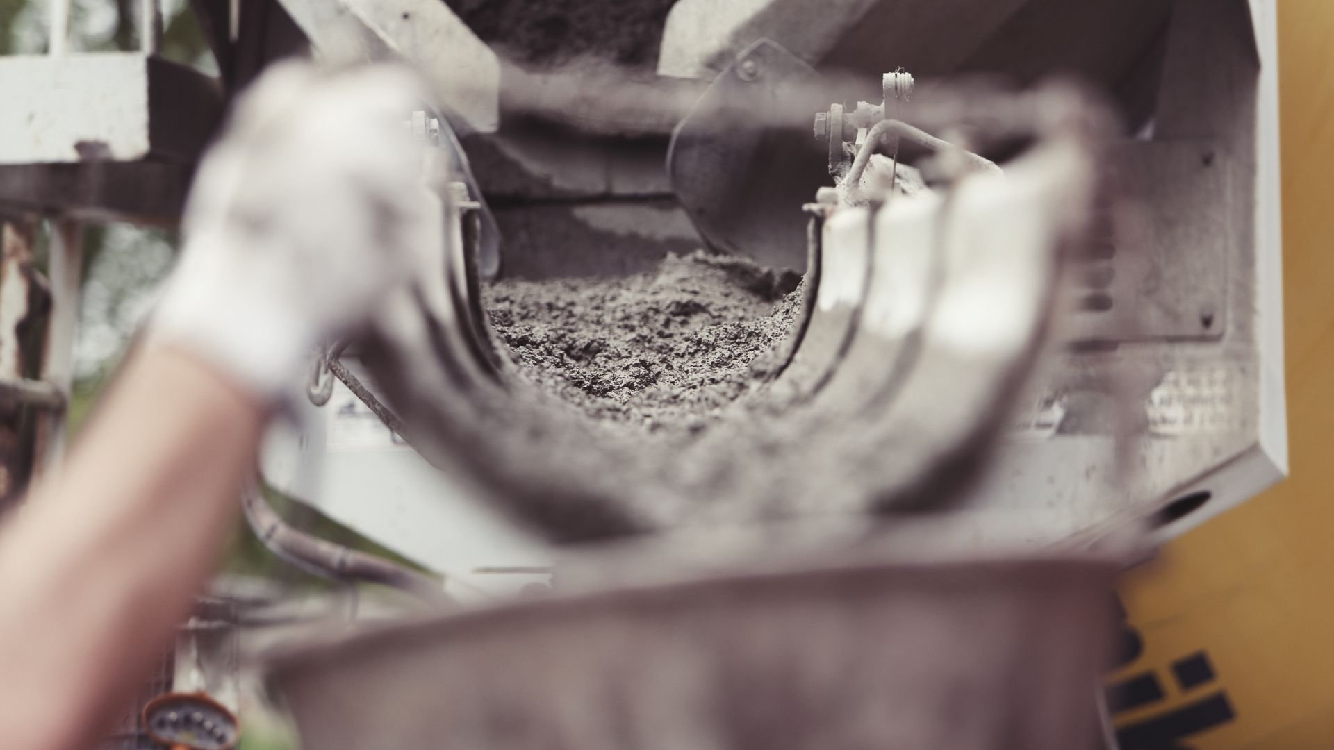 Close-up of cement or soil being poured through industrial machinery