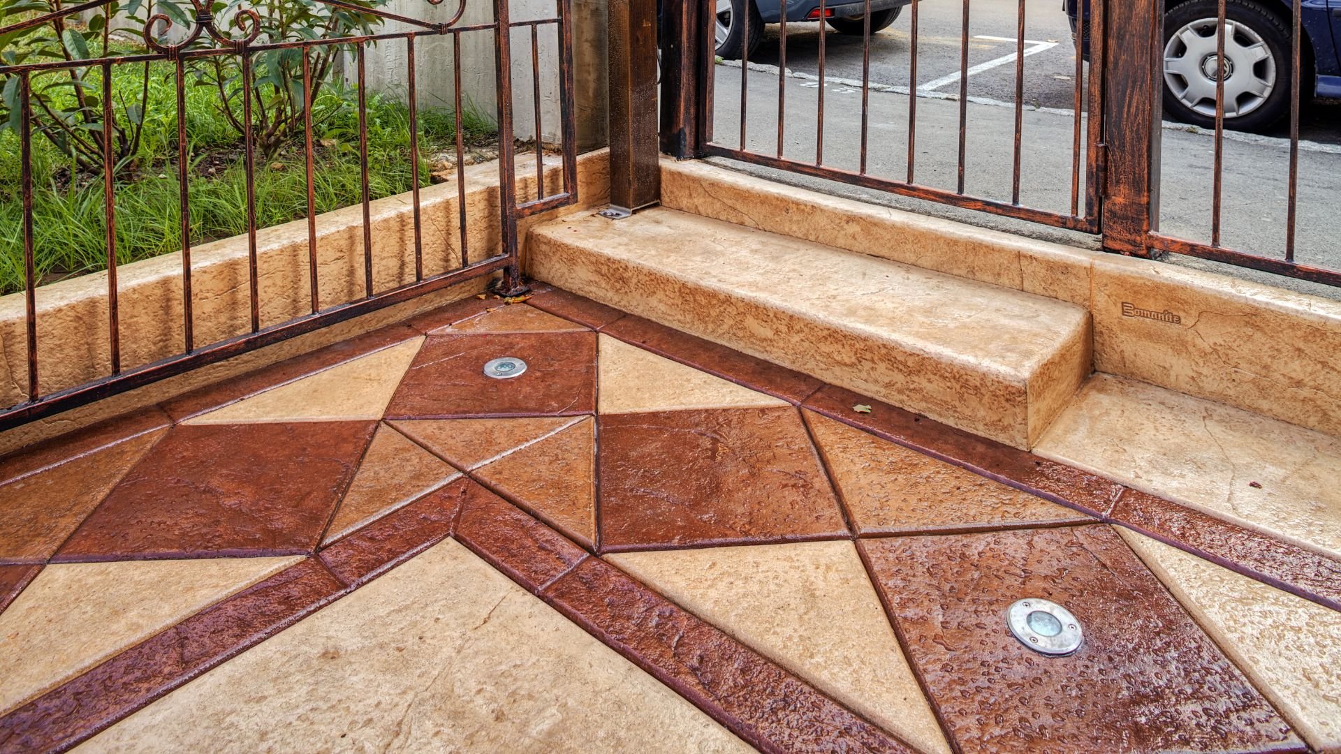 Geometric stone patio with rusty metal fence and decorative ground tiles